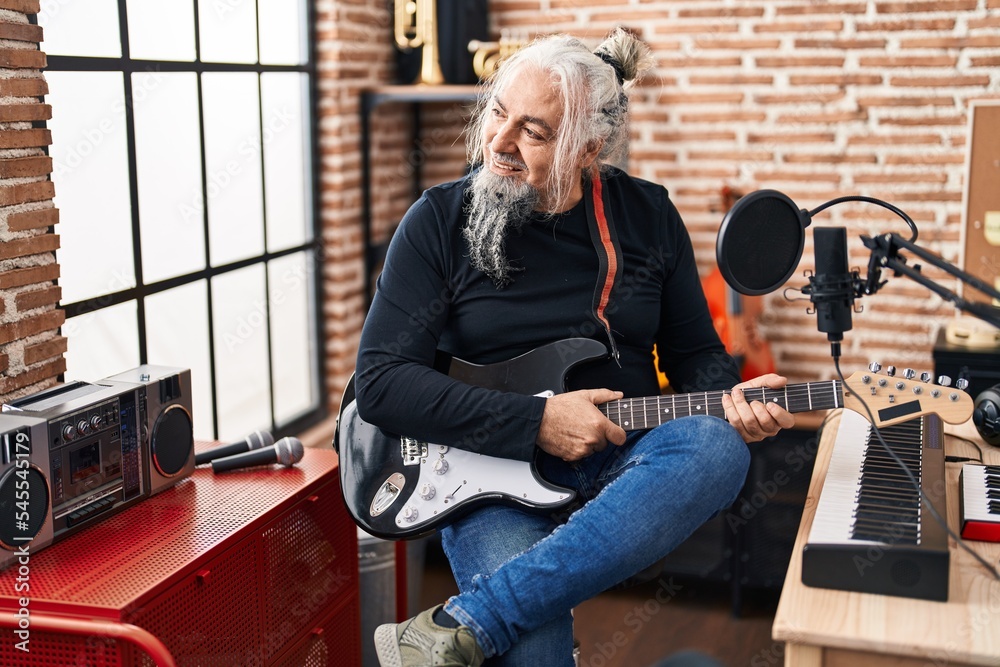 Sticker Middle age grey-haired man musician smiling confident playing electrical guitar at music studio