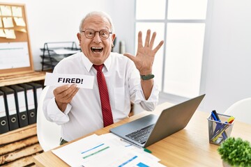 Senior business man holding fired banner at the office celebrating victory with happy smile and winner expression with raised hands