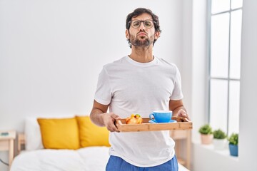 Handsome latin man eating breakfast on the bed looking at the camera blowing a kiss being lovely and sexy. love expression.