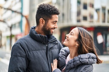 Fototapeta premium Man and woman couple smiling confident hugging each other at street