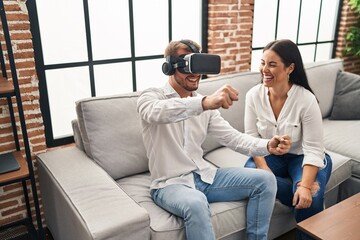 Man and woman couple playing video game using vr goggles at home