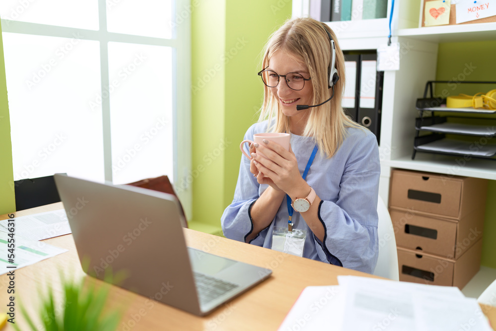 Sticker Young blonde woman call center agent using laptop drinking coffee at office