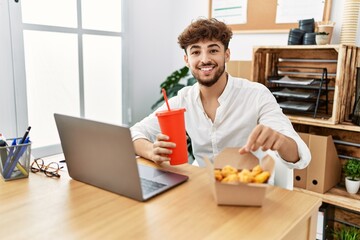 Fototapeta na wymiar Young arab man using laptop having lunch at office