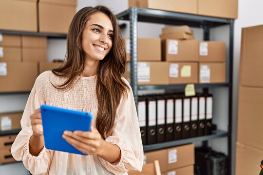 Young hispanic woman smiling confident using touchpad at storehouse