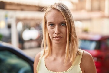 Young blonde woman with relaxed expression standing at street