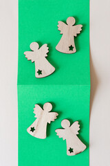 four wooden christmas angel cutouts with star shapes on partly folded green paper