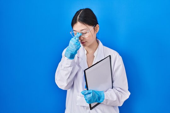 Chinese Young Woman Working At Scientist Laboratory Tired Rubbing Nose And Eyes Feeling Fatigue And Headache. Stress And Frustration Concept.