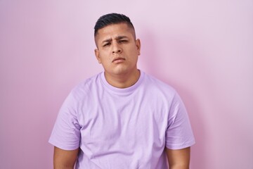 Young hispanic man standing over pink background looking sleepy and tired, exhausted for fatigue...