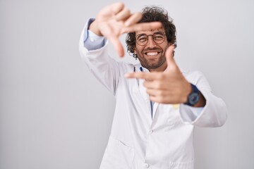 Hispanic young man wearing doctor uniform smiling making frame with hands and fingers with happy face. creativity and photography concept.