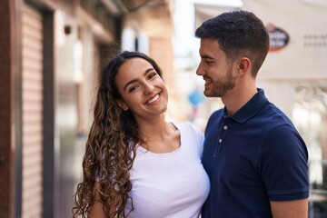 Fototapeta premium Young hispanic couple smiling confident hugging each other at street