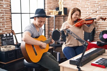 Man and woman musicians playing violin and classical guitar at music studio