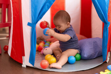 Obraz premium Adorable chinese toddler playing with balls sitting inside of circus tent at home