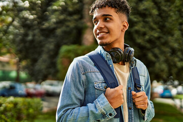 Hispanic young man smiling wearing headphones at the university campus