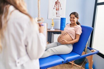 Young latin woman pregnant patient having physiotherapy session at clinic