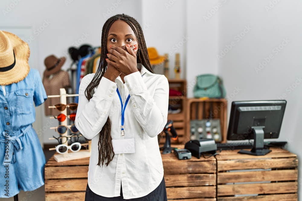 Sticker Black woman with braids working as manager at retail boutique shocked covering mouth with hands for mistake. secret concept.