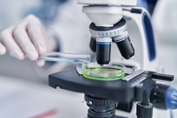 Young hispanic man scientist using microscope at laboratory
