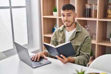 Young hispanic man sitting on table studying at home