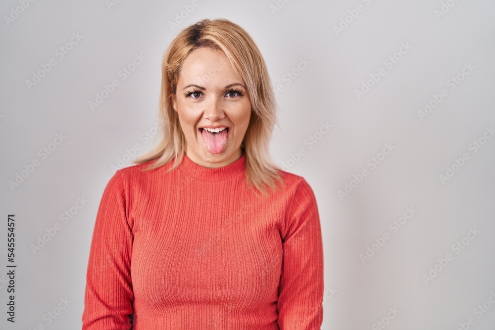 Canvas Prints Blonde woman standing over isolated background sticking tongue out happy with funny expression. emotion concept.