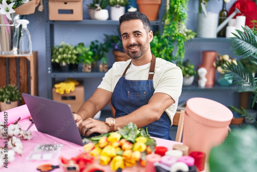 Sticker Young hispanic man florist using laptop working at florist