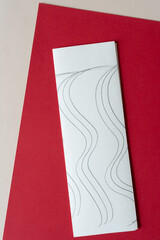folded paper with wavy lines on red and beige