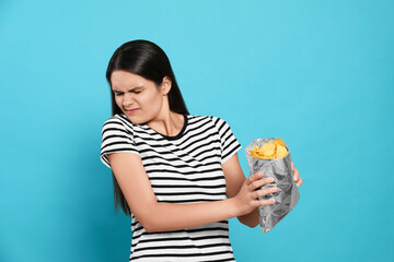 Beautiful woman refusing to eat potato chips on blue background