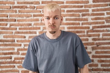Young caucasian man standing over bricks wall depressed and worry for distress, crying angry and...