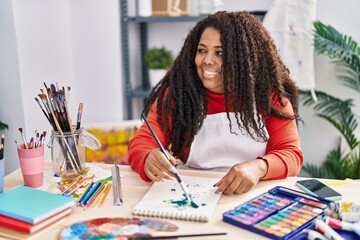 African american woman artist smiling confident drawing on notebook at art studio