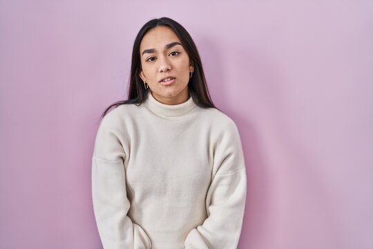 Young south asian woman standing over pink background looking sleepy and tired, exhausted for fatigue and hangover, lazy eyes in the morning.