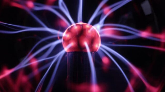 One ball night lamp with a red-lilac moving electric charge that changes its movement from touch on a black background, side view, close-up in slow motion.