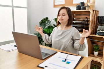 Brunette woman with down syndrome meditating at business office