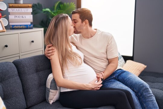 Man and woman couple expecting baby hugging each other kissing at home