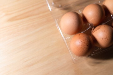 Fresh eggs are placed in a plastic tray with a wooden background.