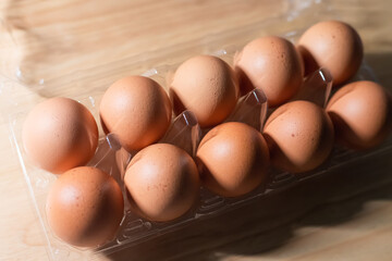 Fresh eggs are placed in a plastic tray with a wooden background.