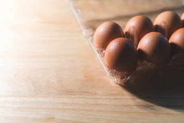 Fresh eggs are placed in a plastic tray with a wooden background.