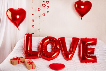 Foil helium balloons with the inscription Love in a room decorated for Valentine's Day or birthday.
