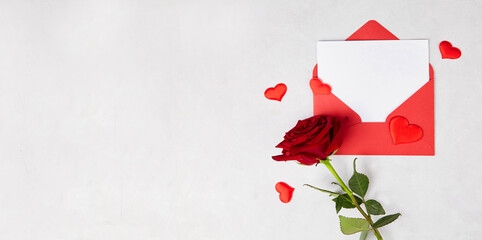 A red rose, a red envelope with an empty piece of paper for congratulations or a declaration of love on a grey isolated background. Banner. Valentine's Day, Mother's Day, Birthday.