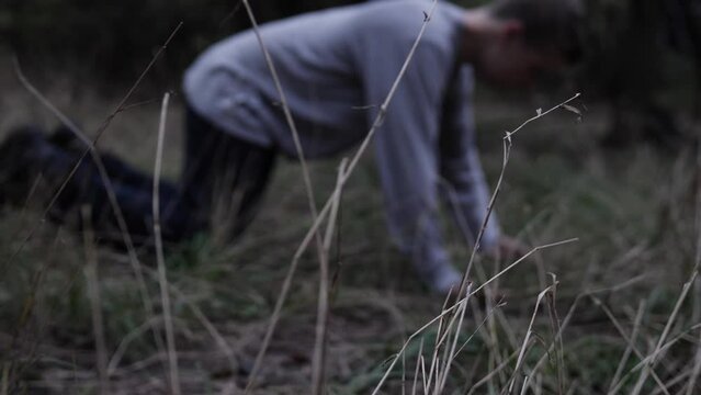 A young man falls to his knees in the woods to pray