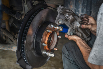 Auto mechanic installing car front brake calipers.