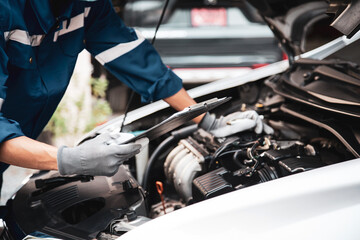 Fototapeta na wymiar Car care maintenance and servicing, Close-up hand technician auto mechanic checking inspection list after repairing change spare part car engine problem and car insurance service.