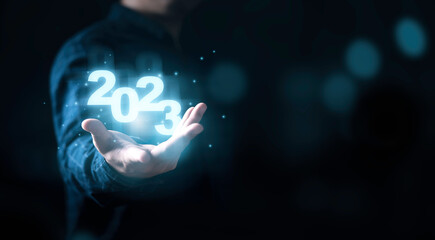 Businessman holding virtual 2022 number with blue bokeh background and copy space for merry...
