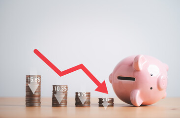 Decreasing of coins stacking and down arrow with fallen pink piggy bank for economic depression...