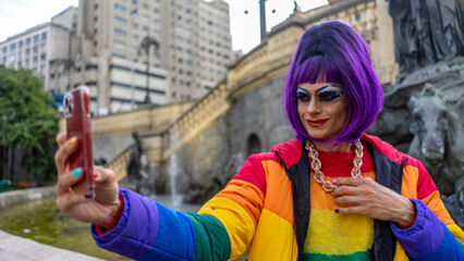 Drag queen in her colorful clothes strolls through the city listening to music and drinking coffee