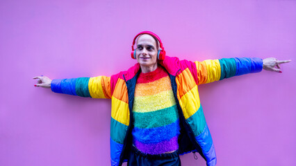 Drag queen in her colorful clothes strolls through the city listening to music and drinking coffee