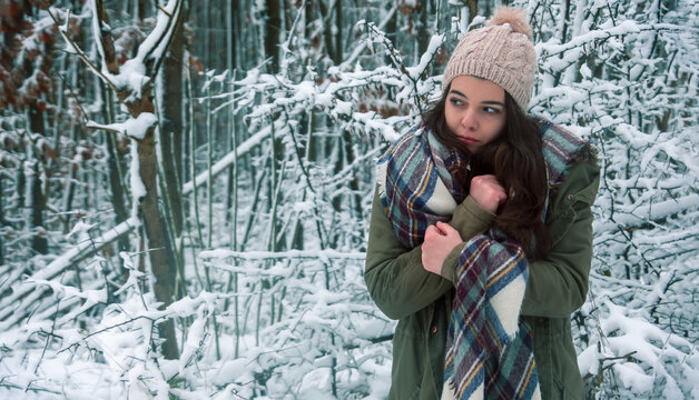 Beautiful Young Freezing Girl Portrait With Scarf, Knitted Hat, Rubbing Her Cold Hands In Snowy Christmas Winter Forest