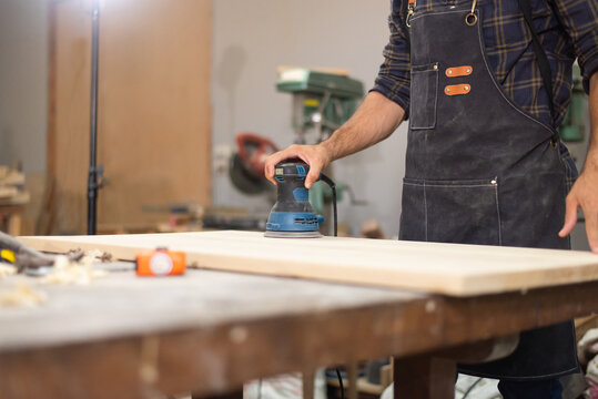 Carpenter man professional skill using electric sander for wood in carpentry shop