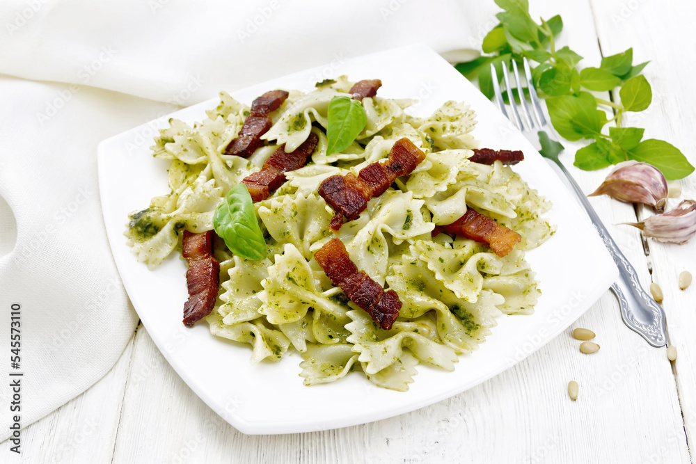 Wall mural Farfalle with pesto and bacon in plate on light board