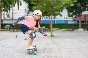 asian child skater or kid girl smile playing skateboard or fun riding surf skate carving in skate park for extreme sports exercise to wearing helmet elbow wrist knee support for body safety protect - obrazy, fototapety, plakaty