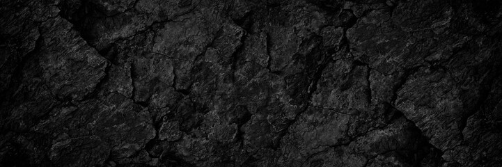 Black rock texture. Rough mountain surface with cracks. Close-up. Dark stone background with space...