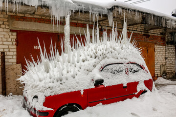 The car under snow is stuck with large icicles, winter: Russia - January 2016
