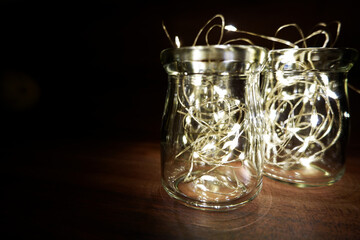 Glittering illumination lighting in a glass bottles on darkness. Simple lighting photo for holiday decorations.